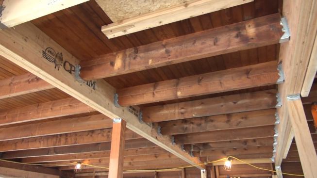 The first floor ceiling (second floor frame) of the old house was originally framed with sawn 2x8 boards more than 26 feet long, spanning the entire downstairs of the house. The floor joists had sagged four inches in the middle of the span. Thompson Johnson cut the joists and two mid-span locations and reframed the floor with two long beams built up with doubled 1.75-inch by 10-inch LVLs, and supported by Douglas Fir posts.