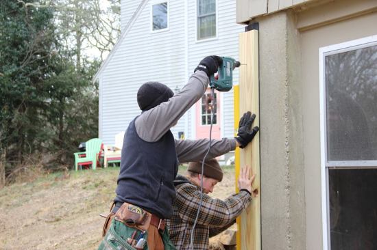 Russ Laffin holds a 2x6 in plumb position while Mike Hill drills a pilot hole for another split-shank fastener. This member is also gasketed to the existing concrete foundation using A BG65 flexible EPDM gasket supplied by Conservation Technologies. The EPDM gaskets offer several advantages: They conform readily to irregular surfaces, are flexible enough to install in sub-zero temperatures, and stay flexible indefinitely in service.