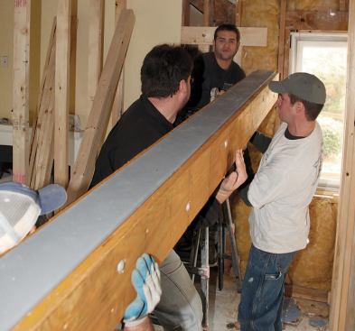 The crew called in extra hands to raise the beam, first setting it on cleats nailed to the walls at each end.