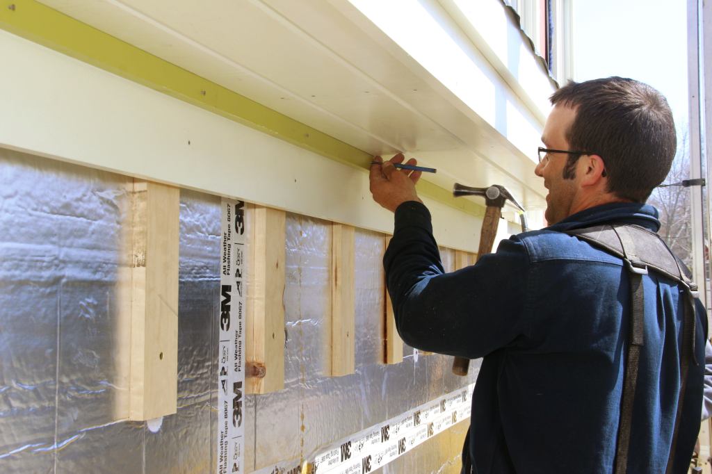 As a final touch, Pollards fastens pre-painted bed molding is over the frieze, setting the nails flush to the surface of the trim. The whole trim package will get a final coat of paint once the siding is complete.