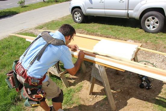 Pollard transfers layout marks from a template onto the porch railing, establishing a three-and-three-quarter-inch space between balusters as required by code.