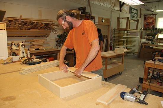 Jeff sets a stretcher into a toe-kick box. This provides a surface to screw the bottom of the cabinet to in the field.