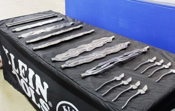 Pieces arrive at the factory as forgings; these were produced at a Klein facility in Elk Grove Village, Illinois. What you’re seeing are pieces of steel at various points in the forging process. The bars on the left were cut from 20-foot steel billets, heated, and forged (hammered between a series of dies) into the lineman’s plier parts at the right end of the table. Look closely and you’ll see that individual parts are knocked out of larger pieces of steel.