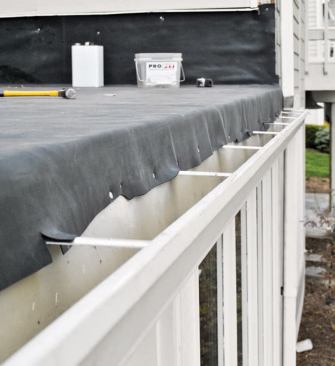 The roofers pull the EPDM tight and tack it in place, leaving it long enough to ensure that water flows into — rather than behind — the gutter.