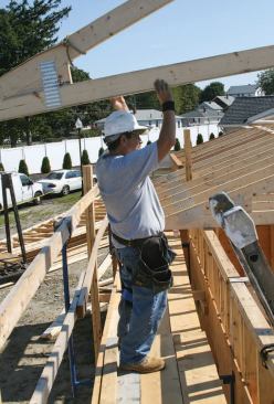 At midlevel, a carpenter is assigned to each wall plate, working from outrigger staging set up on the outside walls or from rolling pipe staging on the deck.