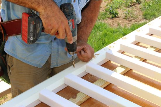Pre-drilling screw holes at the pre-determined spacing for fastening balusters to the bottom rail.
