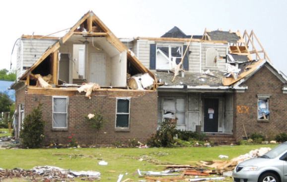 A nearby home also lost gable-end attic trusses in two places. The garage doors (barely visible at the left end of the house) were breached, allowing the gable wall and roof to be blown off.
