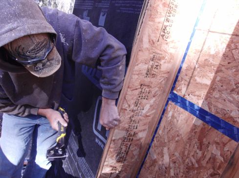 Carpenter Rich Perry staples Solitex Mento Plus breathable "sarking membrane" to the face of a wood I-joist. OSB Joints in the underlying 2x4 stud wall have already been sealed with Tescon Vana vapor-permeable air-sealing tape. The cavity formed by the Mento Plus will be filled with dense-pack cellulose.