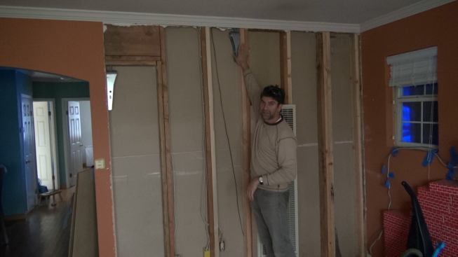 Gregor points out a hold-down at the top of the newly reinforced shearwall, which ties the wall to another shearwall above it, to maintain a continuous load path to manage seismic forces.