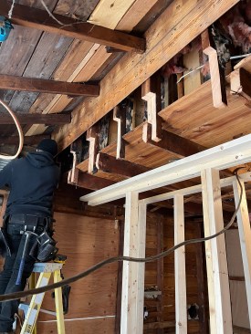 There was little existing support for the second floor and knee wall that supported the roof. With temporary framing installed to support the loads, the crew knotched the studs to receive a new LVL beam. 