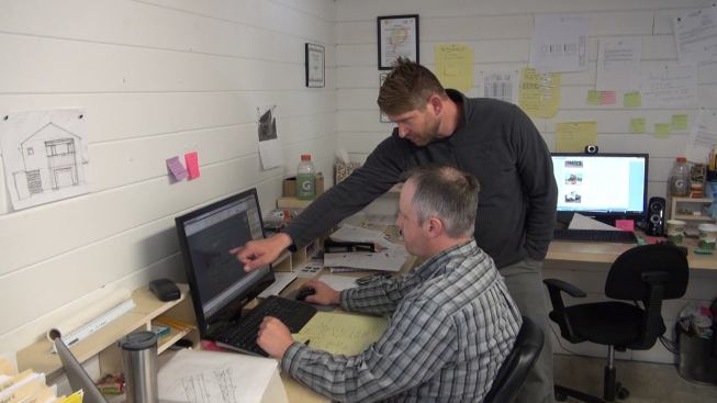 Owner Chris Corson and designer Mike Maines of EcoCor discuss a construction detail in the “Ivory Tower” office above Corson’s panelizing shop in Searsmont, Maine.