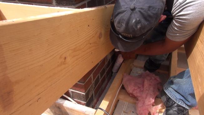 Once all the flashing has been screwed into position, Phillips caulks the joints between the flashing and the brick chimney with high-temperature sealant.