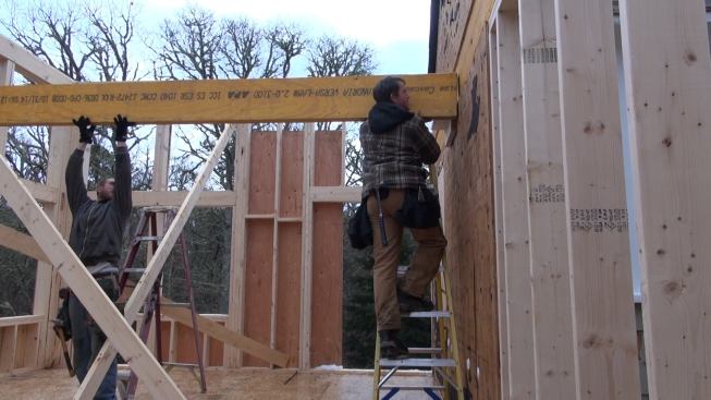 Laffin positions the beam, sliding it along the temporary shelf.