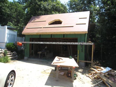Ryan and Mike Dangelo, of M.J. Construction, in Centerville, Mass., framed the garage walls and roof, headering off a rectangular opening in the roof for the eyebrow dormer.