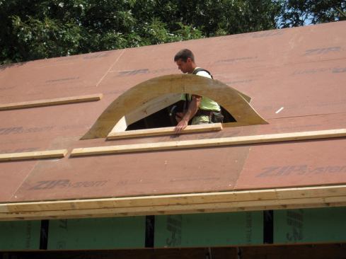 A 2x4, cut at a 45-degree angle and tacked to the roof, held the first rib in position for nailing.