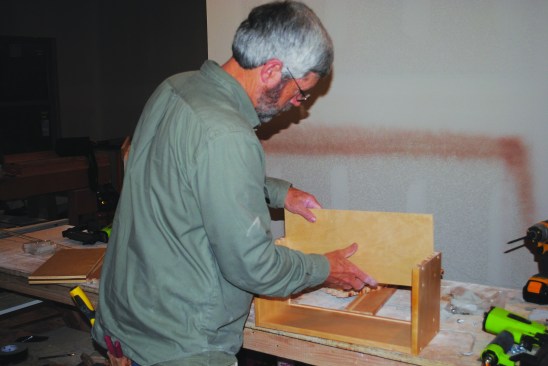 Then he slides the drawer bottom in and taps the other side into place.