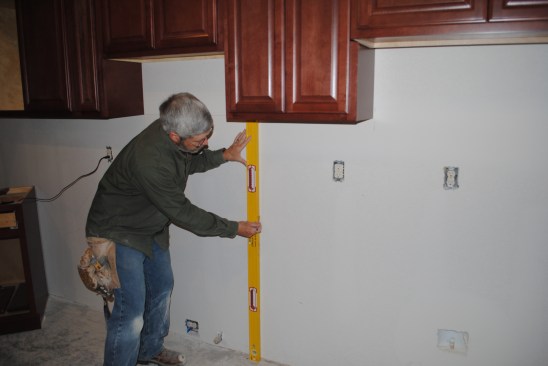 A plumb line positions the base cabinets.