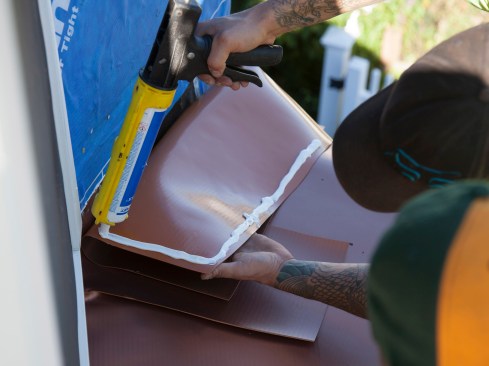 Before the flashing strips are folded up the wall, a full bead of caulk is applied along the upper edge and sides. The author uses a non-sag, elastomeric, neutral-cure silicone sealant—Duro-Caulk Plus by Duro-Last roofing systems.