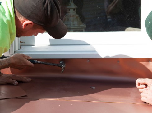 The flashing’s top edge of the vertical leg is nailed off. Usually, the hail heads get covered with overhanging sidewall shingles, or in this case, window trim under the existing sill.