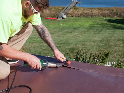 Lastly, the cover flashing’s inside edge is welded to the main roof membrane; the flashing’s outside edge is welded to the drip edge as well. When installed, the PVC cover strip is held back a little bit from the drip edge’s outside edge, so the weld’s bonding can be inspected.