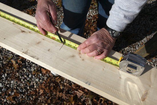 At the other end of the tape, another crew member holds a pencil at the measurement and swings a short, shallow arc. 