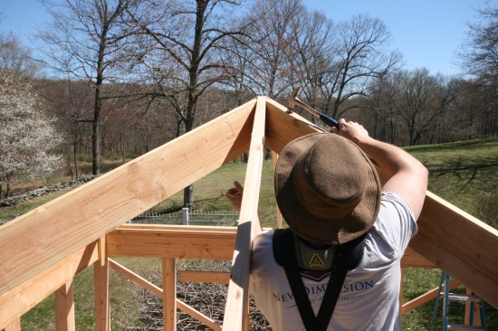 A crew member taps the hip rafter down until the shoulders of the cheek cuts are flush with the king commons on both sides.