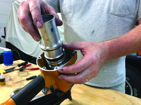 Place the bottom bumper into the frame over the locator plate to help guide the cylinder assembly into place. The shaft of the driver has a groove cut into one side that has to align properly with the locator plate. With the shaft and the locator plate aligned correctly, slip the cylinder assembly into the nailer frame.