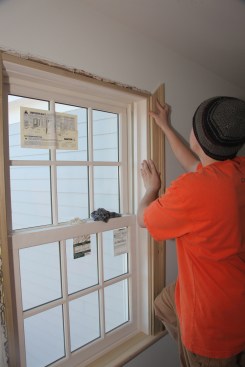 The carpenter sets the casing in place to check the length before tacking the piece in place.