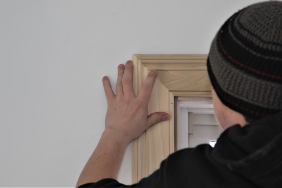 Carprnter uses a finger to remove glue that has oozed out of the joint.