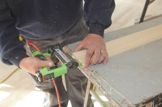 Set the end of the stock on a flat surface to help align the return with the stock. A headless pinner tacks the return in place until the glue has a chance to dry.