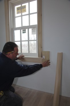 The apron should line up perfectly with the outside edge of the casing. Make a simple jig from a scrap of board with a straight edge. Cut a piece out of one edge that is larger than the overhang of the stool horn. Then push the top of the jig against the casing and slide the apron over to bottom of the jig. Be sure that the longest part of the apron profile hits the jig. 