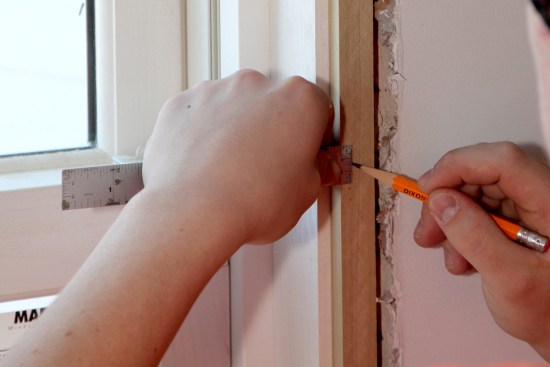 The carpenter uses a 6-inch steel ruler to mark the reveal for the casing on the extension strip. Note the reveal between the jamb and the extension strip installed earlier.