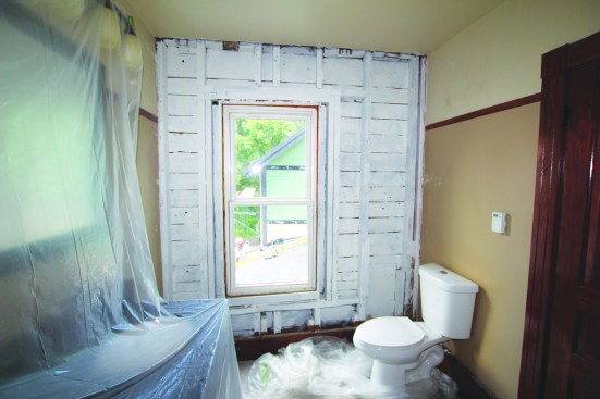 In the main house, plaster, lath, and insulation from the walls facing the fire-damaged barn were removed. Here, the existing framing is primed in a second-story bathroom.