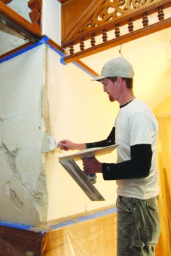 William Bisson applies brown coat to the damaged textured walls.