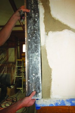 He uses a slicker to gauge the straightness of the brown coat at corners.