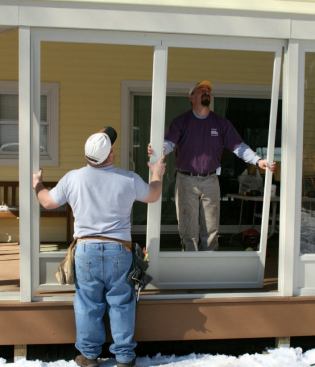 We slide the joined pair of panels up into the deeper top track until they clear the bottom of the opening, then drop the panels into the base track.