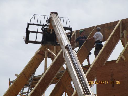 Framers position an LVL rafter used to define a dormer opening in the roof.