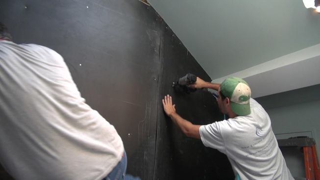 The crew nails the last piece of vinyl into place. After this, a drywall contractor will come on site to re-apply drywall to the wall.