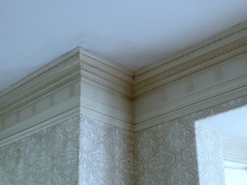 This entablature detail along the ceiling if the room is a close cousin of classic entablature with an elaborate cornice or crown, a frieze and a picture rail below.