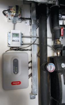 The set-point control (the white box with the screen) is programmed to activate the pump when the fluid in the collectors is 15°F hotter than the water in the tank. The gray box beneath the set-point control houses the zone controller, which activates the zone dampers and air handler when a thermostat calls for heat.
