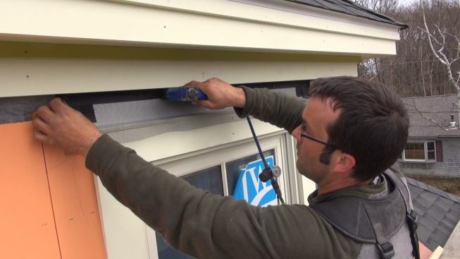 Tacking the window screen into place with a stapler.