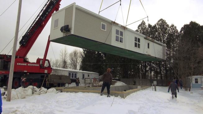 Crew members work to view the unit from all angles as the crane negotiates the path to the foundation.