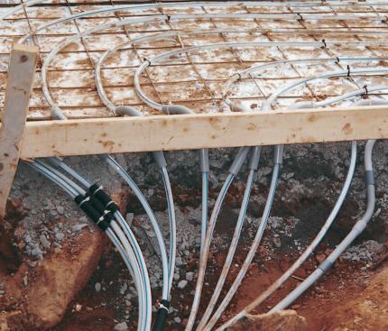 Sleeves of PVC conduit protect the tubing where it passes through the foundation wall and up into the driveway slab. The conduit on the far right  carries low-voltage wiring for the heat sensor embedded in the drive.