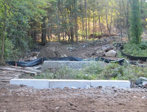 At grade, the abutments transition from plain rectangular blocks to blocks with a precast faux-stone face.