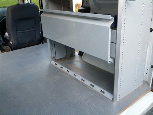 The shelving unit offers several compact storage options. At the bottom is a compartment with a lift-up door.