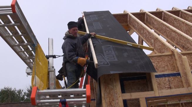 Todd installs a nailer over the Mento Plus fabric, nailing into the face of the I-joist build-out on the wall.