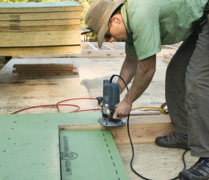 The author uses a router to cut out door and window openings; he's found that router bits tend to wear faster when cutting Zip panels than they do when cutting standard OSB sheathing, probably because of the denser material and resin-impregnated overlay.