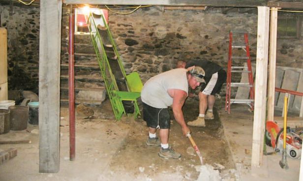 One of the first orders of business was to provide a center bearing wall in the basement. After cutting through the thin slab, the author's crew dug a trench the length of the basement for a new reinforced concrete footing.