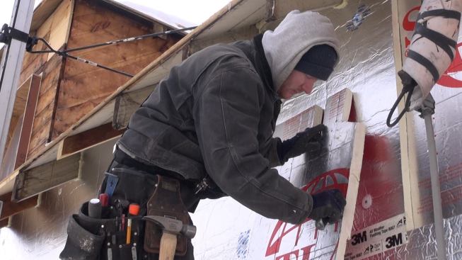 Mitchell trims the edge of the insulation sheet with a knife. Corners and eaves create challenging and laborious detail work on this project.