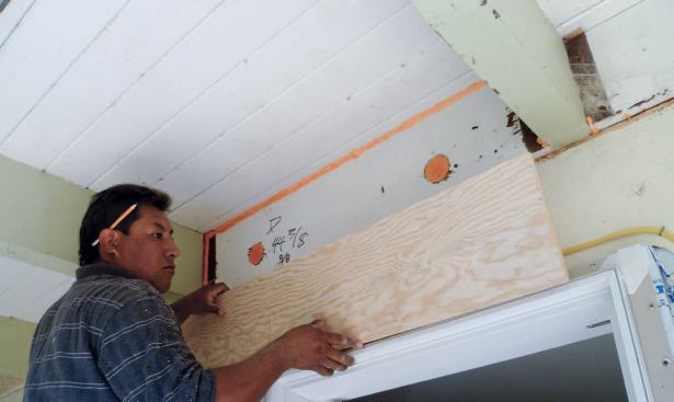 Plywood bedded in polyurethane foam seals air leaks between blocking and rafter tails. A stucco wall finish will cover the raw bottom edge of the plywood. A nearby rafter bay has been sealed with tape instead of foam — a time-consuming but more positive solution.